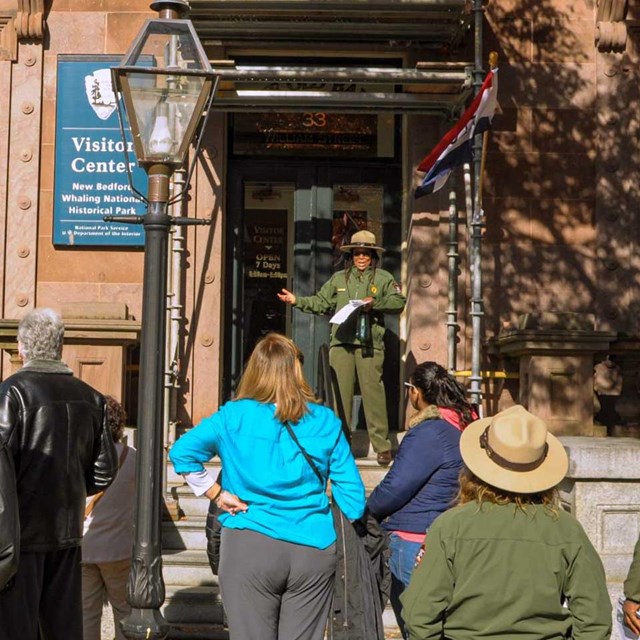 Large crowd standing in front of a ranger giving a tour