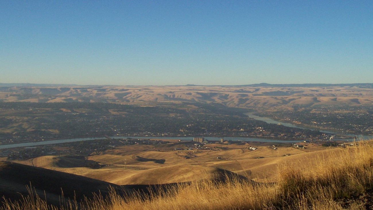 A view of two rivers merging into one river from above on a sunny day.