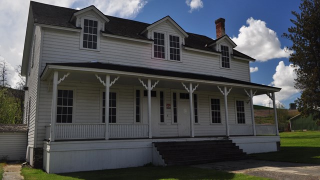 A white two story building with an outer porch. 