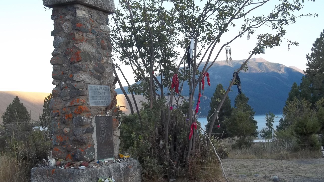 A monument with a lake in the background as the sun sets.