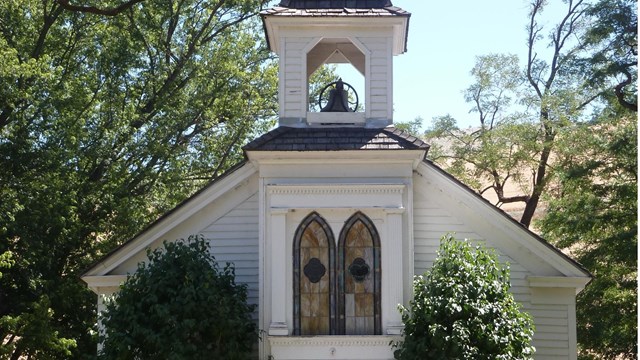 A white church with a cross on top of the steeple.