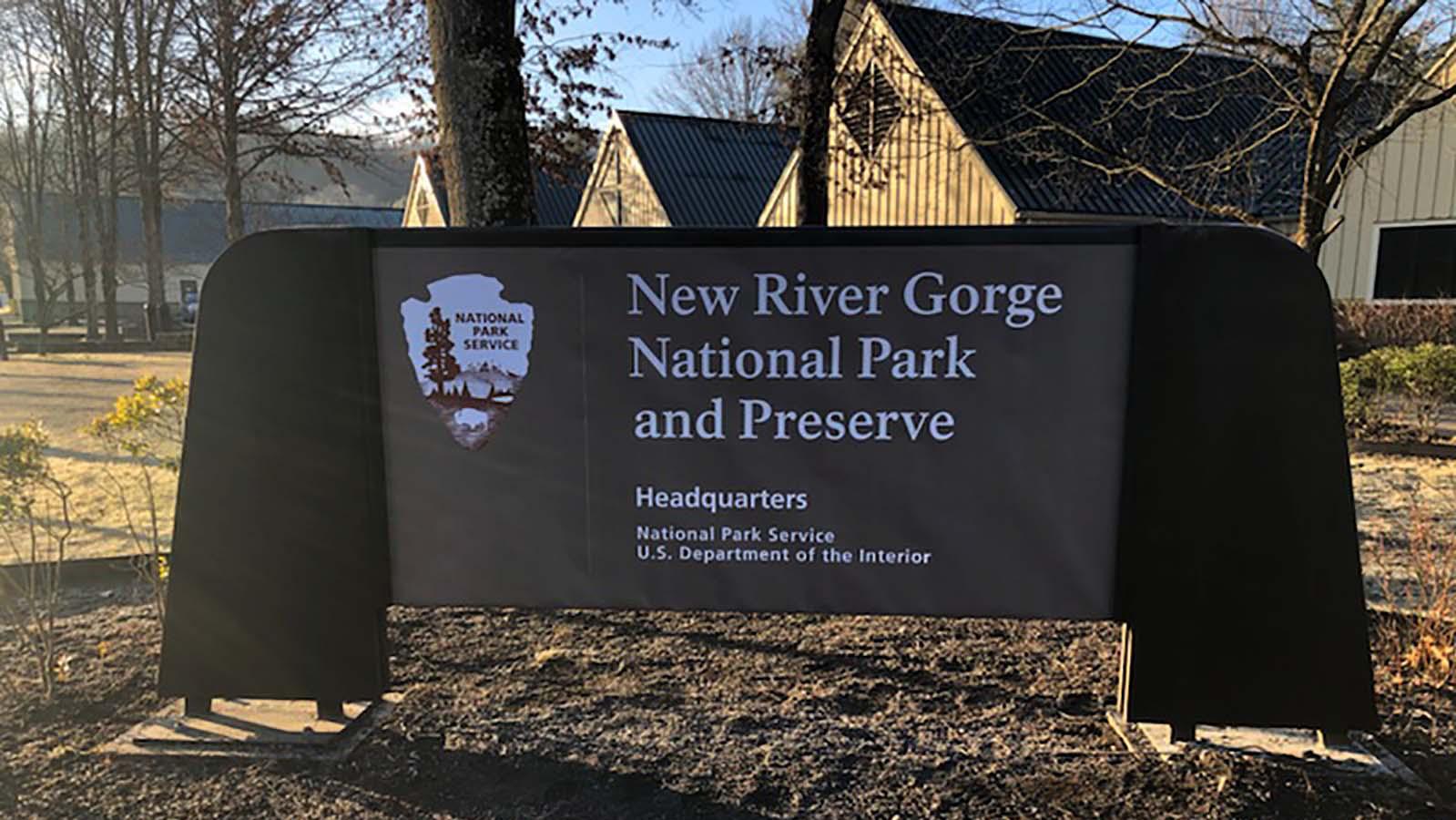 park sign with arrowhead in from of a large tan building