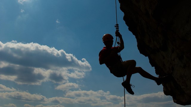 rock climber silhouetted on cliff