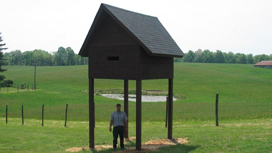a large bat house with maintenance worker underneath