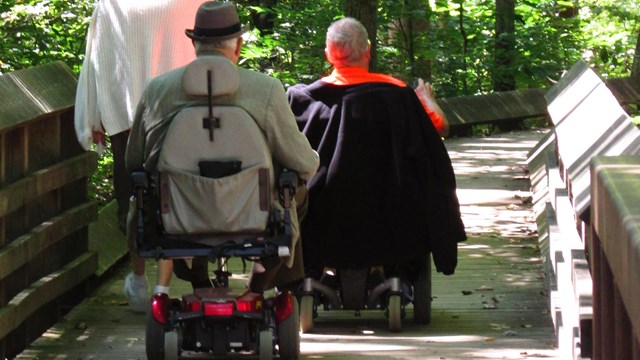 visitors in wheel chairs on boardwalk trail