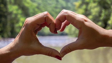 Two hands form a heart over the river