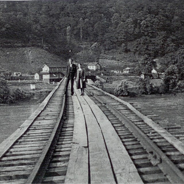 historic photo of bridge crossing a river and leading to a town