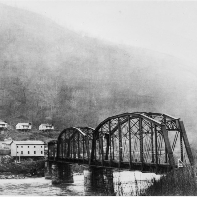 historic photo of bridge across river with a town on the other side