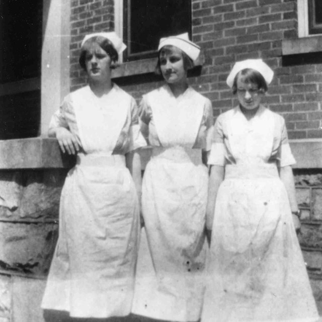 historic photo of nurses in front of a hospital 