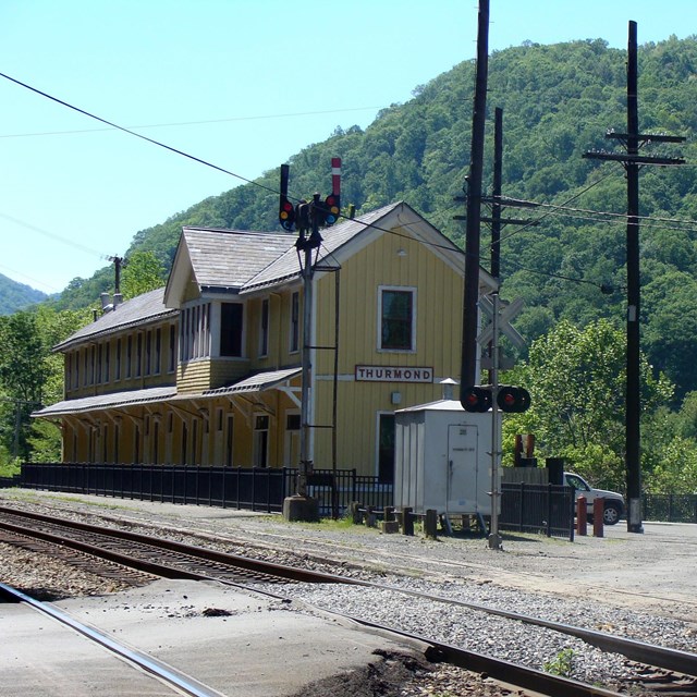 A yellow wooden building next to two railroad tracks