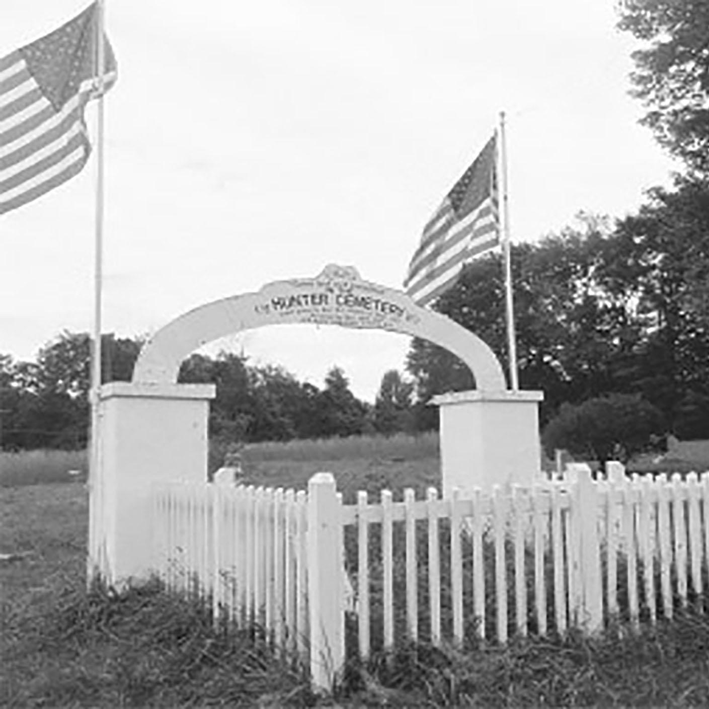 black and white photo of an old cemetery with gate and fence