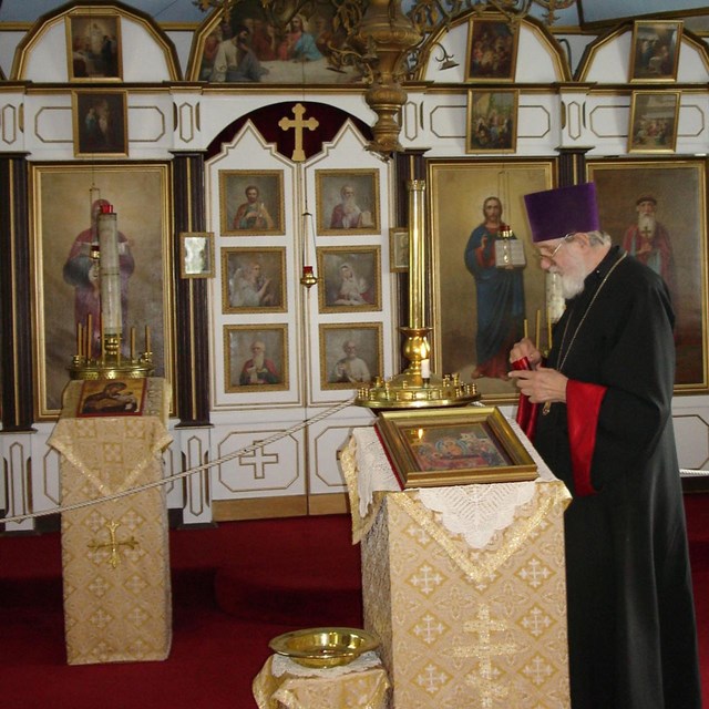 A photo of the iconostasis screen and Rev. Macarius Targonsky standing next to the icon stand