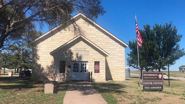 A limestone building with an American flag and park sign