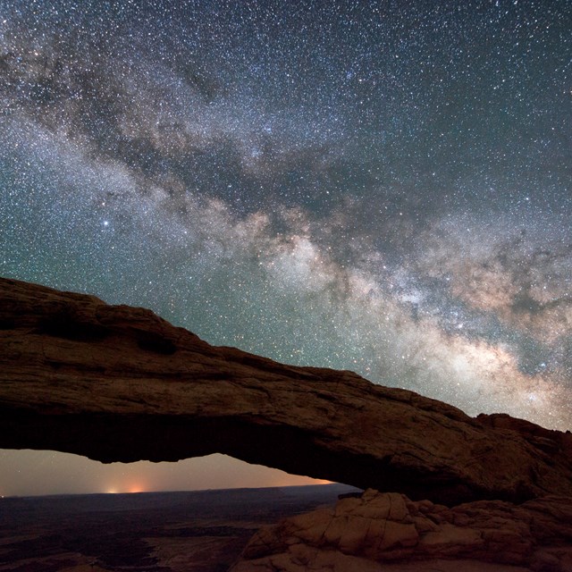 the milky way in the night sky above a rock arch