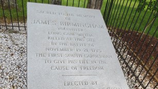 Flat gray stone monument dedicated to James Birmingham.