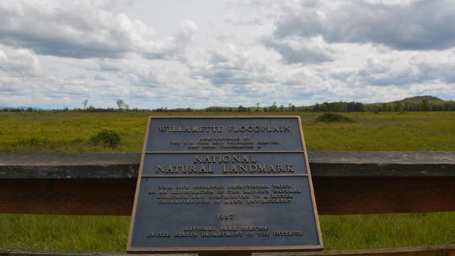 a national natural landmark plaque overlooking a field