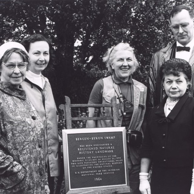 black and white photo of people standing by plaque