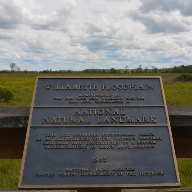 a national natural landmark plaque overlooking a field
