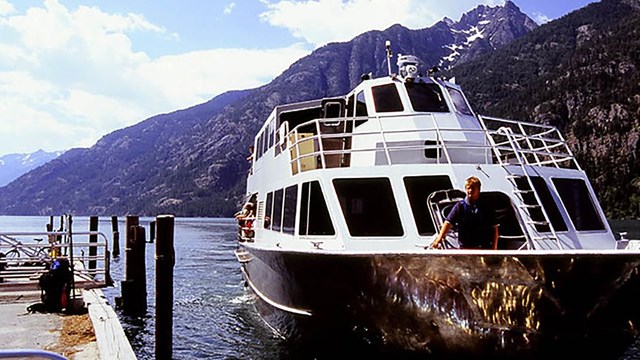 Ferry boat approaches a wooden dock. 