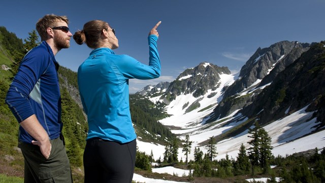 two people looking and pointing at mountains.