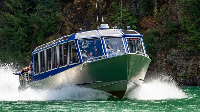 a blue motor boat moving on a green lake