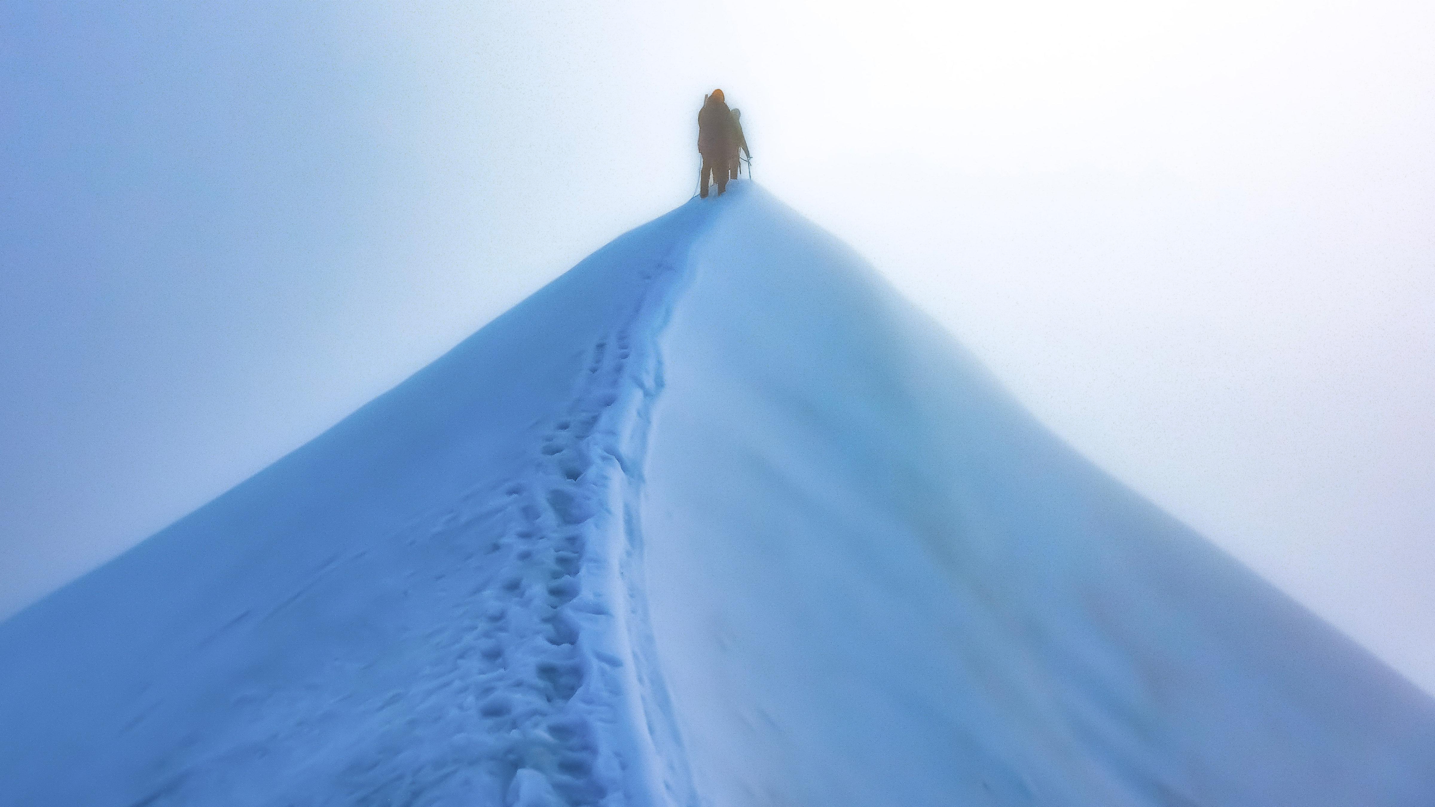 hikers along a narrow snowy ridge