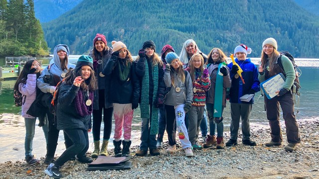 Ten students stand with three instructors on a rocky lakeshore