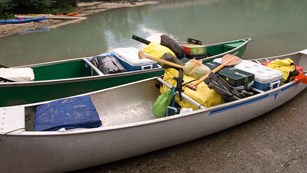 Canoes loaded for camping prepare to launch at the lakes edge.