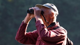 A man looks through binoculars.