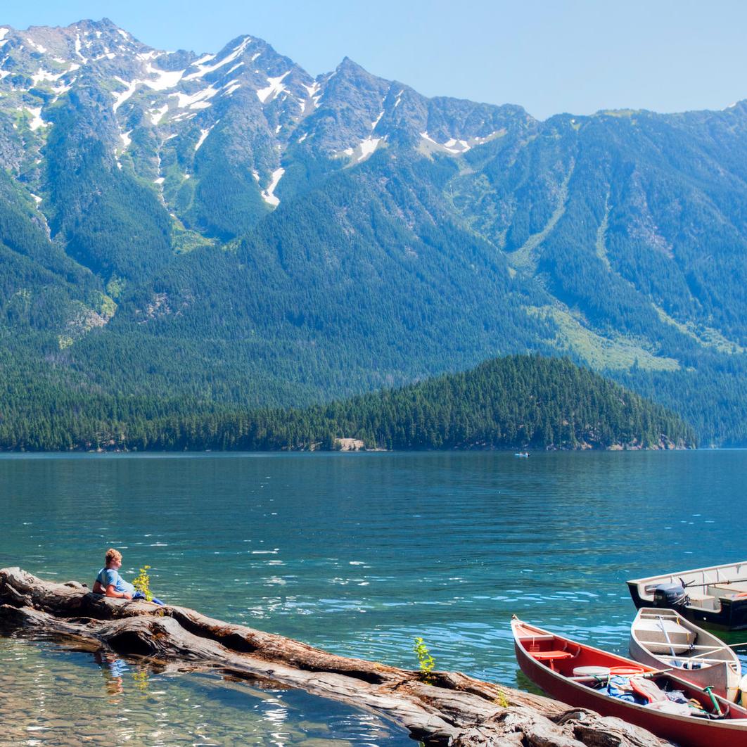 Canoes float on a lake with mountains in the background.