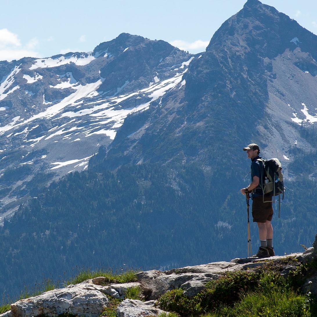 A hiker stands at an overlook on a mountaintop.