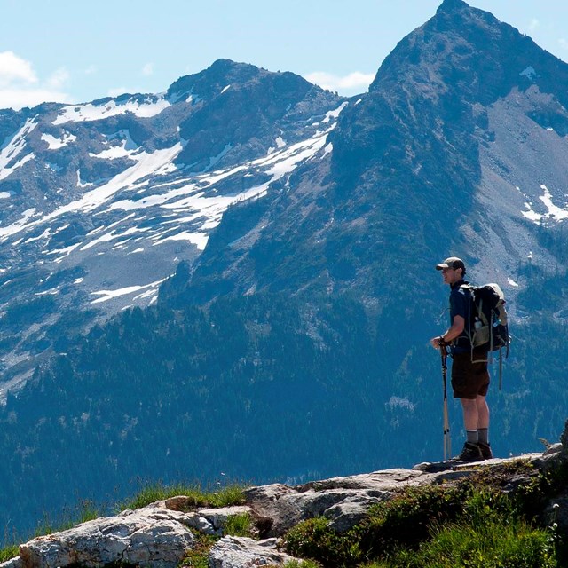 A hiker stands at an overlook on a mountaintop.