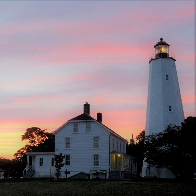 Sandy Hook Light house in front of a sunset