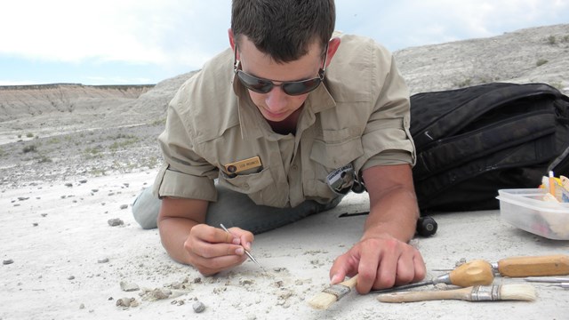 Intern laying on a rock looking at GIS information 