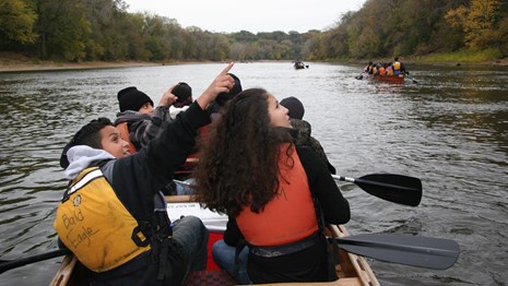 Group of kids on a boat on a river pointing to something