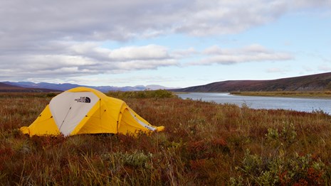 Yellow tent in a field near a river