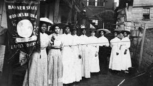 Black and white photo of Black women holding up suffrage signs