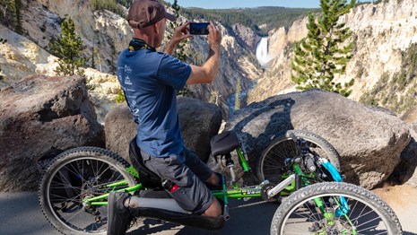 Visitor in a wheelchair taking a picture of a waterfall