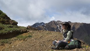 Visitor sitting with a notepad in a mountainous area