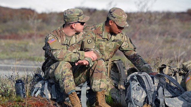 Two army soldiers sitting on ruck sacks