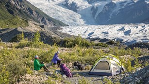 Campers with a tent and gear set up in a valley