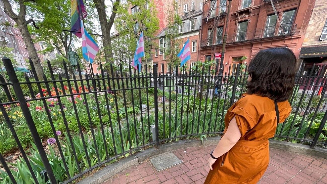 Visitor looking at a flower garden decorated with pride flags