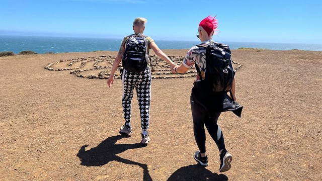 Couple walking through a sandy area overlooking an ocean