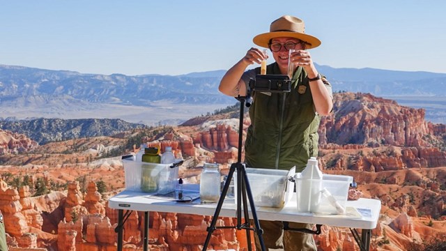 Ranger giving a virtual science program in front of a big canyon