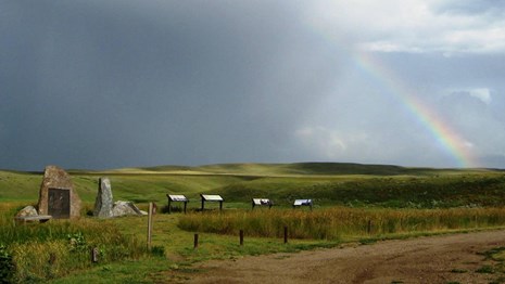 Rainbows over a grass field with interpretive panels