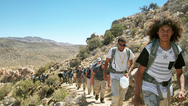 Line of Youth Conservation Corps members hiking on a desert trail