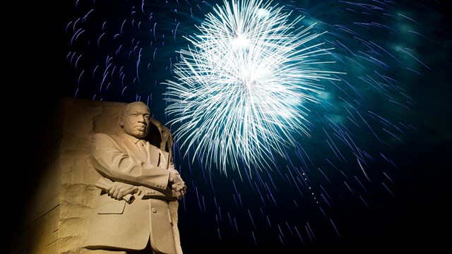 Blue firework near a statue of Dr. Martin Luther King Jr.