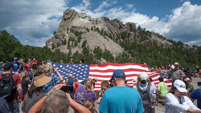People and a flag below Mount Rushmore