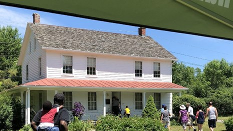 Tour group walking inside a two-story white house