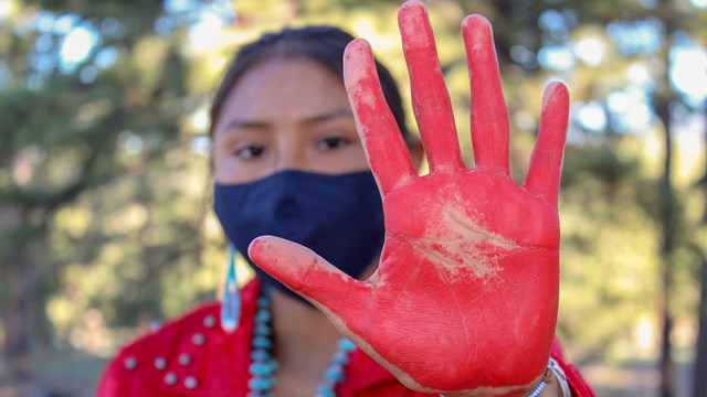 Person holding her hand up which is painted red 